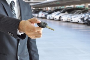 Businessman hand giving a car key - car sale & rental business c